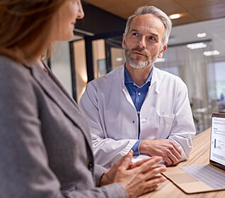 A clinician and a customer discussing data over a laptop