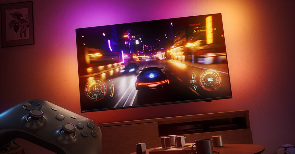Vāji apgaismotā telpā Philips Ambilight televizorā tiek rādīta sacīkšu videospēle