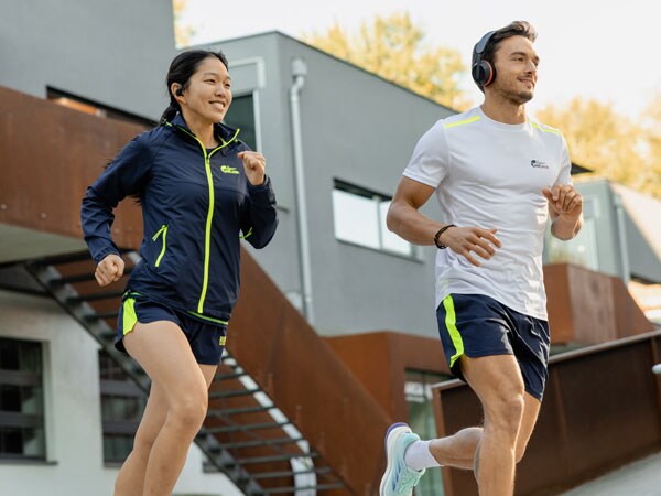 Divi skrējiena dalībnieki skrien ar savām Philips austiņām.