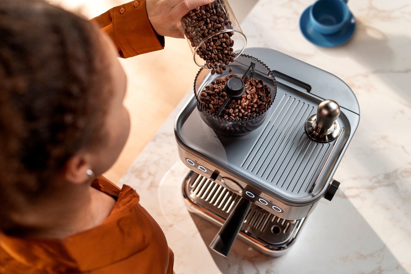 Jauna sieviete ber kafijas pupiņas Philips Barista Brew​ pupiņu tvertnē
